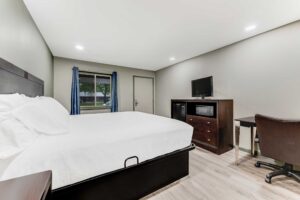 King bed, night stand, wooden unit with fridge, microwave and TV, desk with chair, laminate flooring