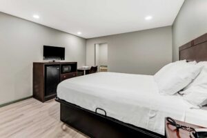 King bed, night stand with telephone, wooden unit with fridge, microwave and TV, desk with chair, laminate flooring