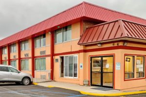 Hotel entrance with double glass doors, two story building, parking spaces