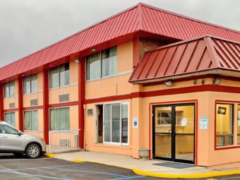 Hotel entrance with double glass doors, two story building, parking spaces