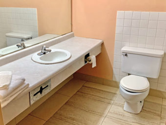vanity unit with towels, mirror, toilet, tiled flooring