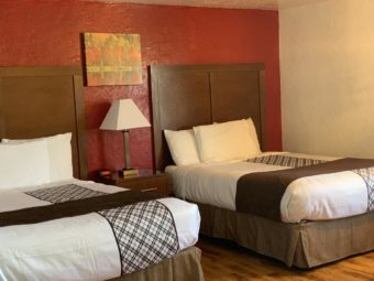 Two queen beds, night stand with bedside lamp and clock, wall mounted art, laminate flooring