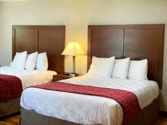 Two queen beds, night stand with bedside lamp and clock, laminate flooring