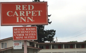 Two story building with exterior room entrances and walkway, brand signage