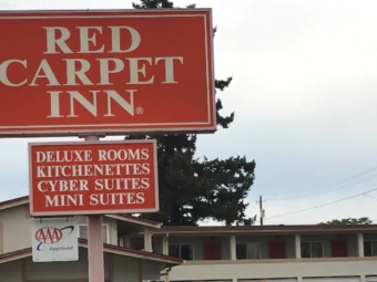 Two story building with exterior room entrances and walkway, brand signage