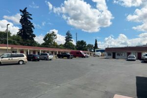One story building with exterior guest room entrances and covered walkways, parking spaces