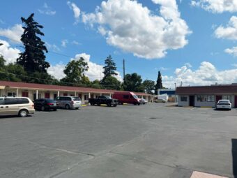 One story building with exterior guest room entrances and covered walkways, parking spaces