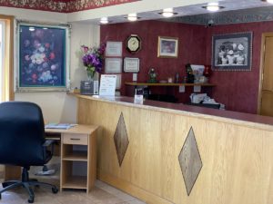 Guest Check in desk, desk with office chair, wall mounted art, tiled flooring