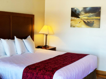 King bed, night stand with bedside lamp and clock, art image
