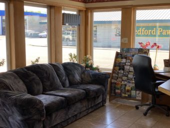 Sofa, guest information leaflet stand, desk with office chair, tiled flooring