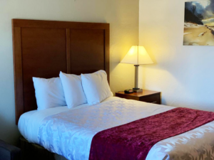 Queen bed, night stand with clock and bedside lamp, art image