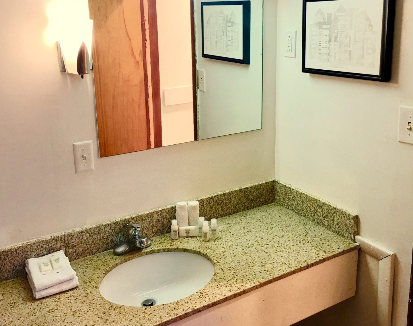 Vanity unit with sink, bathroom amenities, wall mounted mirror and light