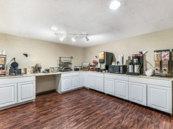 breakfast displar counter with waffle machine, fruit, microwave, coffee pots, juice dispenser, cereal dispensers, toaster, laminate flooring