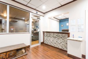 Guest check in desk, wooden bench seat, window and door into breakfast area, tiled flooring