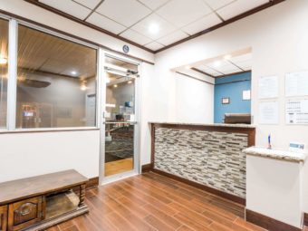 Guest check in desk, wooden bench seat, window and door into breakfast area, tiled flooring