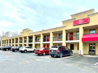 Hotel entrance, two story building with exterior room entrances, covered walkways, parking spaces