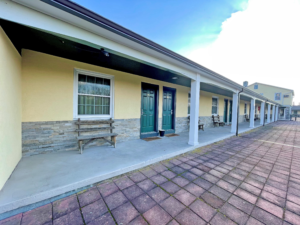 Exterior room entrances with covered walkways and wooden benches outside rooms