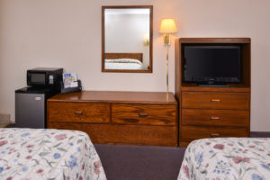 Two queen beds, fridge, microwave, wooden unit, mirror, wall mounted lamp, wooden unit with tv, carpet flooring