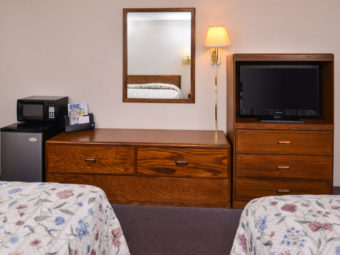 Two queen beds, fridge, microwave, wooden unit, mirror, wall mounted lamp, wooden unit with tv, carpet flooring