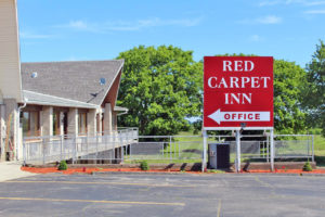 Brand signage, two story building, large trees in background