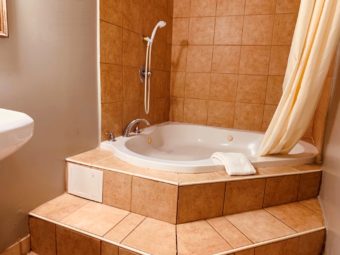 spa tub with bath mat and shower curtain, tiled surround