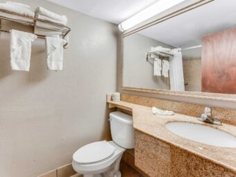 Vanity unit, toilet, mirror, shelf with rail and towels