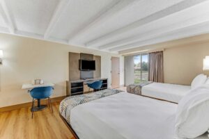 Two double beds, desk with chair, wooden unit with TV and chair, laminate flooring