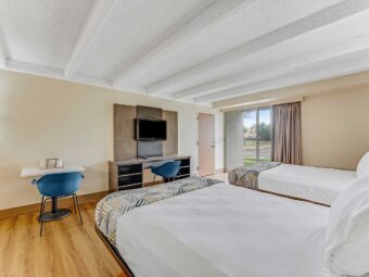 Two double beds, desk with chair, wooden unit with TV and chair, laminate flooring