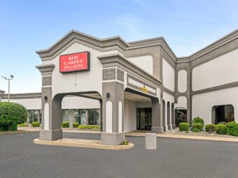 Brand signage, hotel entrance, two story building, small bushes