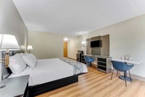 King bed, night stands, wall bedside lamps, wooden unit with TV, chair, desk with chair, fridge with microwave, wall light, laminate flooring