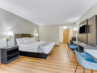 King bed, night stands with telephone, wall bedside lamps, wooden unit with TV, chair, desk with chair, laminate flooring
