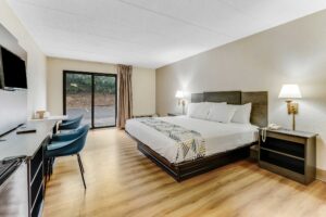 King bed, night stands with telephone, wall bedside lamps, wooden unit with TV, chair, desk with chair, laminate flooring