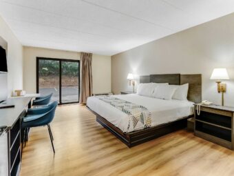King bed, night stands with telephone, wall bedside lamps, wooden unit with TV, chair, desk with chair, laminate flooring