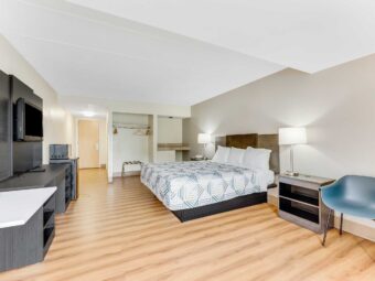 King bed, night stands with bedside lamps and telephone, chair, wooden unit with TV, fridge with microwave, hanging rail with hangers, folding portable luggage rack, laminate flooring