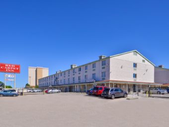 Three story building, brand signage, gated parking, grassy areas and small bushes