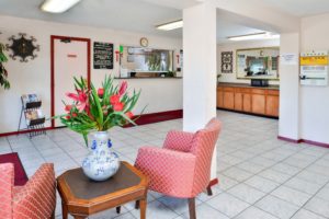 guest check in desk, easy chairs, occasional table with vase with flowers, tiled flooring