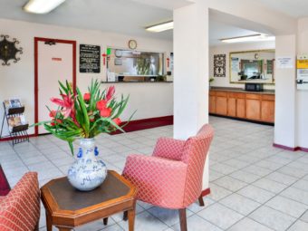 guest check in desk, easy chairs, occasional table with vase with flowers, tiled flooring