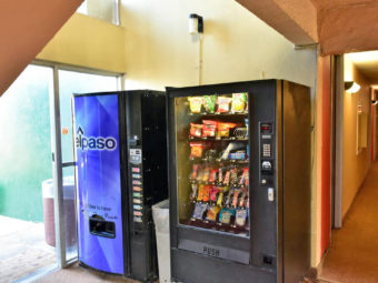 Snack and soft drinks vending machines, doorway to the exterior and interior corridor with carpet flooring