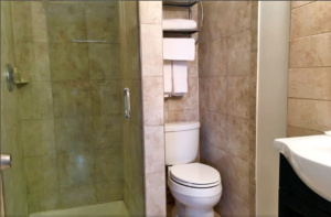 Shower, separate cubicle with toilet, shelves with towels, sink