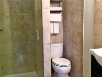 Shower, separate cubicle with toilet, shelves with towels, sink