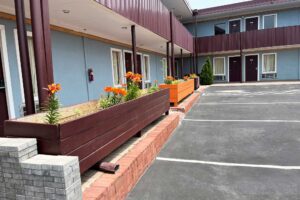 Two story building with exterior guestroom entrances and covered walkways, parking spaces, wooden flower boxes