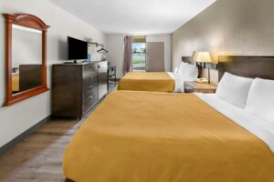 Two queen beds, night stand with telephone, wall bedside lamps, desk with chair, hanging rail with hangers, ironing board and iron, wooden unit with TV, mirror, laminate flooring