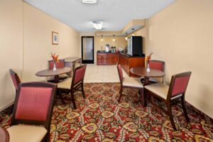 Tables and chairs, counter with breakfast items and chilled cabinet, carpet and tiled flooring