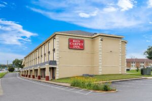 3 story building, landscaping with flowering shrubs and grassy areas, parking spaces