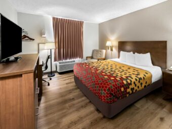 King bed, night stand with telephone, wall bedside lamp, easy chair, floor lamp, desk with chair, ironing board and iron, hanging rail with hangers, wooden unit with microwave, TV and fridge, laminate flooring