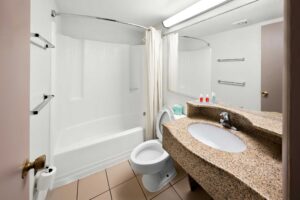 Shower tub with shower curtain, toilet, mirror, vanity unit, towel rails, tiled flooring