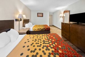 Two queen beds, night stand with telephone, wall bedside lamps, art image, wall light, mirror, wooden drawer unit with TV, laminate flooring
