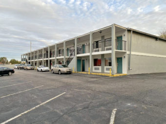 Two story building, walkways and stairs to exterior room entrances, parking spaces