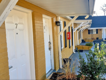 one story building with exterior room entrances, planters with small bushes and plants, parking spaces