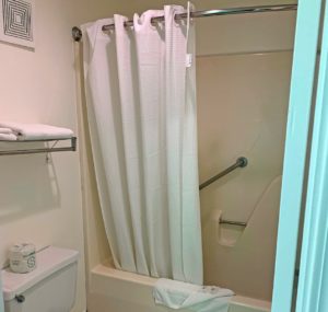 Shower tub with bath mat, bathroom amenities and shower curtain, wall mounted towel rail with folded towels